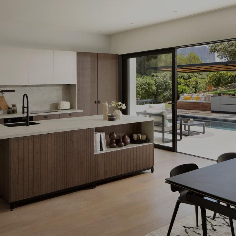 Architecture cuisine moderne avec grand îlot central en bois clair et plan de travail en pierre pour une ambiance chaleureuse et fonctionnelle